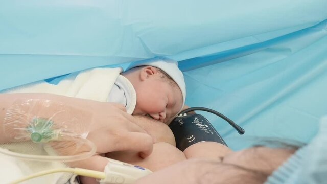 Medium-Wide shot of a newborn baby feeding for the first time after birth.