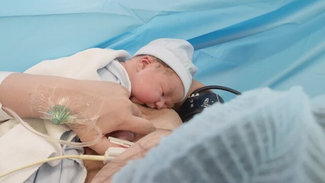 Mother and newborn in the delivery suite.  Newborn feeding for the first time after birth.