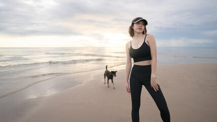 Woman walking along a beach with dog in the morning.