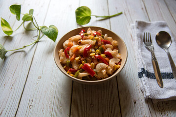 Close up of macaroni pasta with vegetables in a bowl on a background