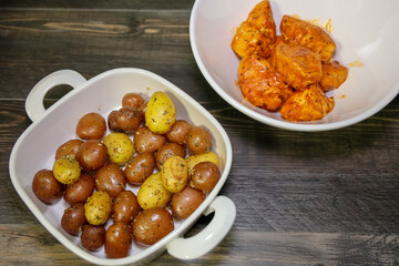 Roasted creamer potatoes with olive oil and herbs. Chicken with red sauce on the background.