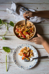 View from top of hands serving pasta from a bowl to a plate