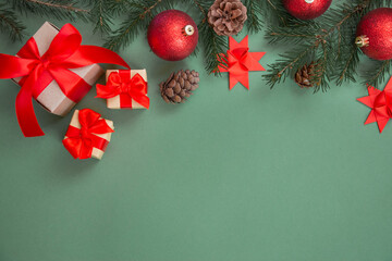 Christmas composition. Gifts with a red bow, spruce branch, New Year's decorations on a green...