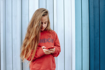 Beautiful young girl with long hair is messaging or playing in smartphone