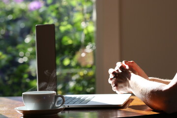 Woman working at home with laptop and a hot water drink