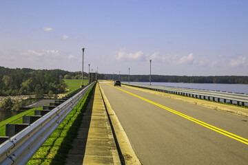 A car traveling across a bridge by a lake