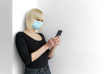 COVID-19 contact tracing application on mobile. A woman dressed in black clothing wearing a surgical medical mask texting smartphone. Prevent coronavirus with geolocation tracking app.