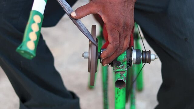 Top view of a man sharpening gardening scissors on a makeshift mobile sharpening machine on a manual bicycle frame.
