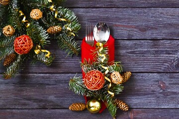 Christmas dinner. Christmas Day. Christmas table place settings. Cutlery on the red napkin, christmas decoration on a  wooden background. copy space, flat lay.