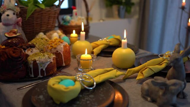 Decorated Easter table with candles, eggs, plates and Easter bunnies - follow focus and pan