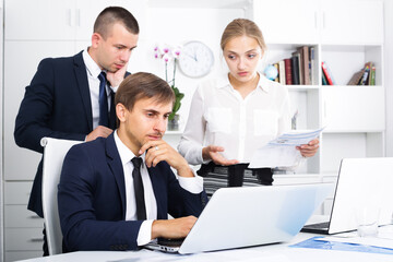 three concerned business colleagues discovering mistake in business calculations in office.