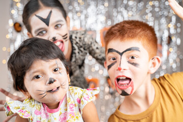 Group of kids in Halloween costumes gesticulating and making scary or spooky faces on decorated...