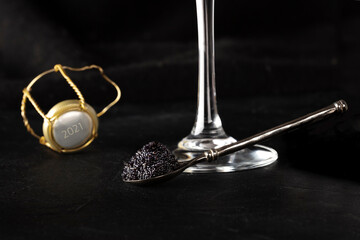 2021 New Year celebration with black caviar and champagne, on a dark background with a place for text