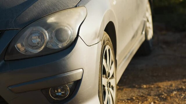 Grey car headlights off sunset golden hour lighting dolly up dusty hood