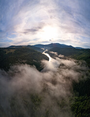 Aerial view clouds over the forest and lake at sunrise. View from drone. Aerial top view cloudscape. Transylvania, Romania
