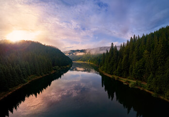 Aerial view clouds over the forest and lake at sunrise. View from drone. Aerial top view cloudscape. Transylvania, Romania
