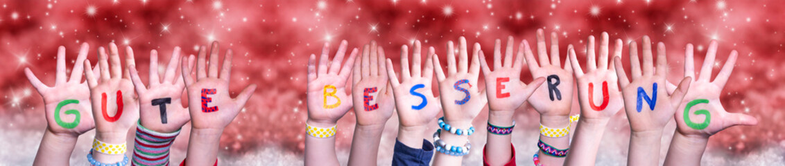 Children Hands Building Colorful German Word Gute Besserung Means Get Well. Red Snowy Christmas Winter Background With Snowflakes And Sparkling Lights