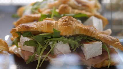 Quick lunch brake. Close up of croissant filled with cheese, cranberry sauce and Prosciutto on a showcase in a cafe