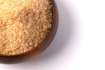 Brown sugar in a wooden cup on a white background