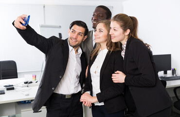 Cheerful multinational business group taking selfie in coworking space