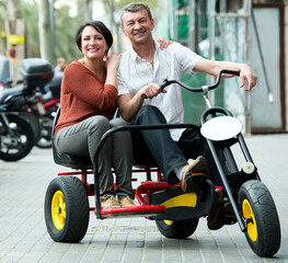 Fototapeta na wymiar Happy couple traveling through city by twin bicycle