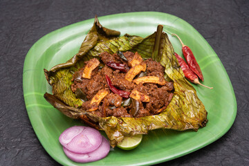 Beef curry Kerala style meat beef or mutton curry garnished with fried coconut slices and curry leaves in banana leaf south Indian style. Bowl of tasty mutton roast with Indian spices