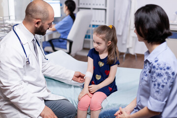 Mother with child having injured hand at doctor for consultation. Healthcare physician specialist in medicine providing health care services treatment examination.