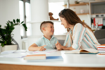 Mother helping her son with homework at home. Little boy learning at home