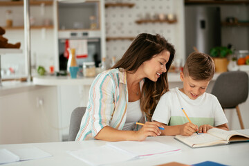 Mother helping her son with homework at home. Little boy learning at home