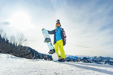 Snowboarder freerider in the mountains is preparing to descend on the background of snow-capped mountains
