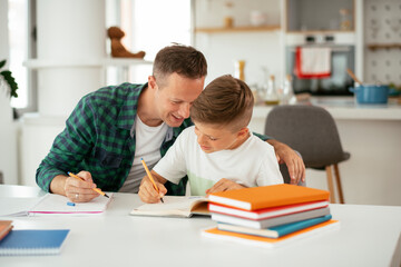 Father helping his son with homework at home. Little boy learning at home.