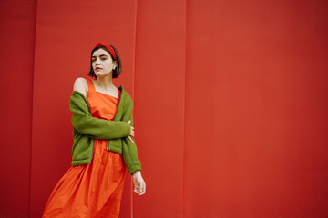 Posing beautiful young girl in red dress and green jacket. Dreaming hoping future in love mood. Expressive artistic conceptual composition. Banner poster size and style series of photos. Bob hair cut