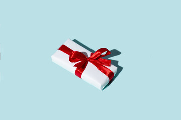 Holiday gift. Happy Birthday. Special day surprise. Festive greeting. White box with red ribbon bow isolated on blue empty space background.
