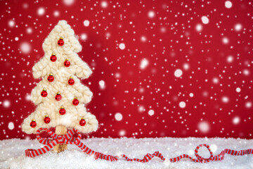 White Fabric Christmas Tree With Snow And Red Background. Decoration Like Red Ribbon And Snowflakes. Copy Space For Advertisement