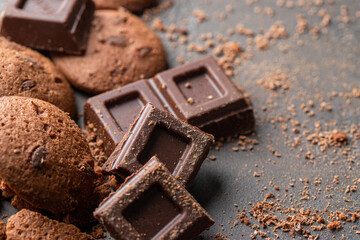 Sweet background, chocolate slices, cookies and mixed nuts on concrete background with copy space.