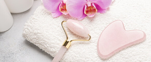 Horizontal banner with Gua Sha massager and face roller on stone background. Massage tool for...