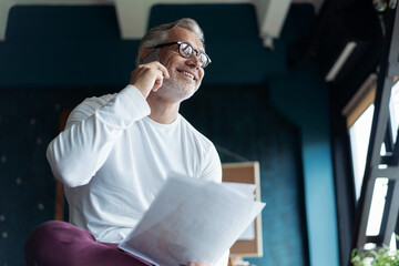 Fototapeta premium Attractive Casual Grey-haired Mature businessman looking at document while talking on phone