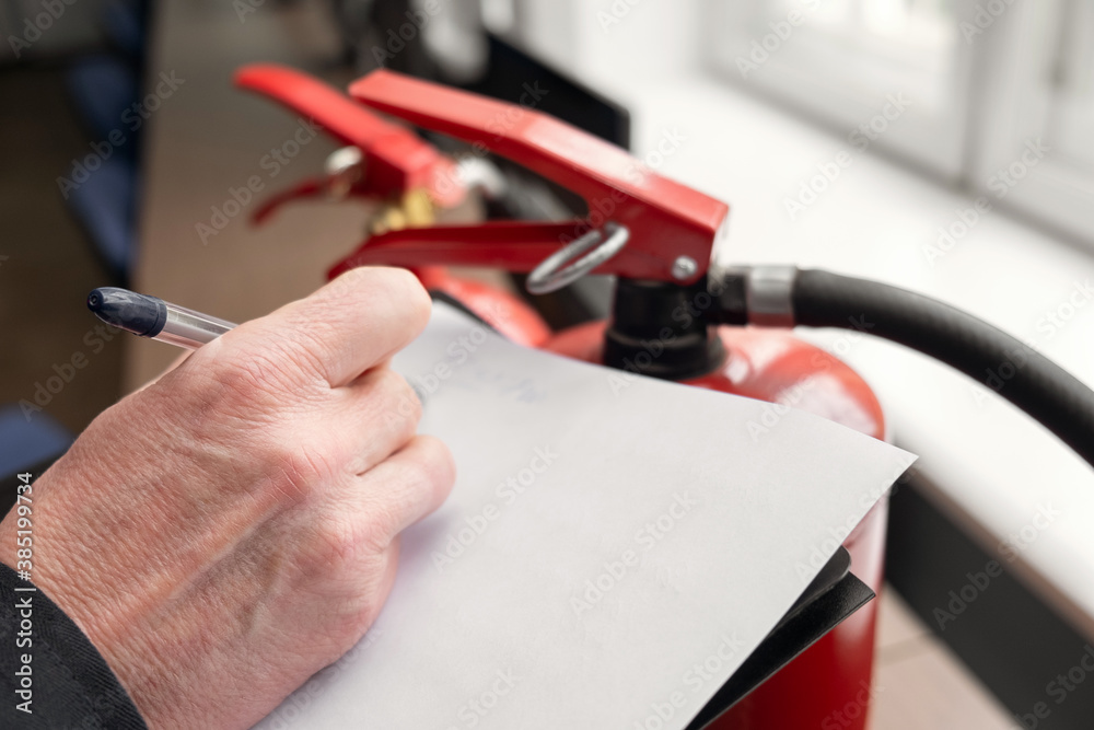 Wall mural engineer professional are checking a fire extinguisher and writes data to the check log. fire alarm 