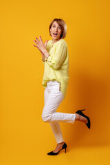 Fototapeta na wymiar Excited woman. Surprise motivation. Wow discovery. Portrait of impressed inspired mature lady in yellow white smart casual outfit isolated on orange background.