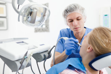 Professional dentist examining and performing treatment to young woman. High quality photo