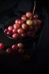 uva rosada sobre un plato y fondo negro