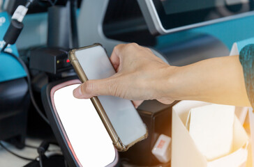 Obraz premium Close up of Woman hand paying with NFC technology on mobile phone in coffee shop, Female customer client pay in cafe with cellphone via pos machine