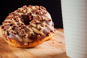 Fresh tasty chocolate with sugar icing donuts on a wooden board white tea cup in fore ground. Black background. Bakery product