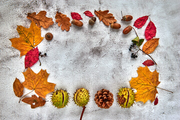 Autumn frame made of dried leaves, branches, pine cones, berries, acorns and hand with cup of coffee on dark concrete background. Template mockup fall, halloween. Flat lay, copy space background