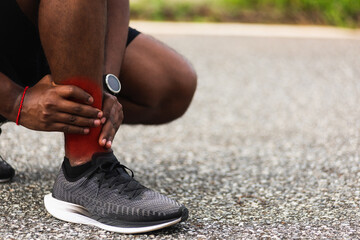 Close up Asian young sport runner black man wear watch hands joint hold leg pain because of twisted ankle broken while running at the outdoor street health park, healthy exercise Injury from workout