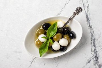 Bowl of delicious green and black olives with mozzarella in oil