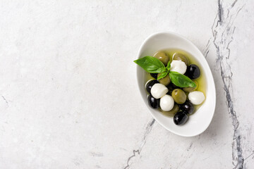 Bowl of delicious green and black olives with mozzarella in oil