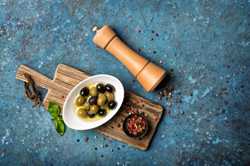 Bowl of delicious green and black olives in oil with pepper mill © viktoriya89