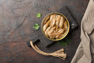 A can with golden sprats fish in oil on black wooden board