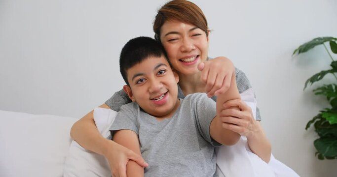 Portrait of happy family with mother and disabled son sitting on sofa at home.